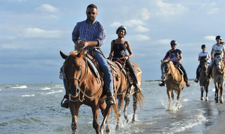People riding horses along the beach.