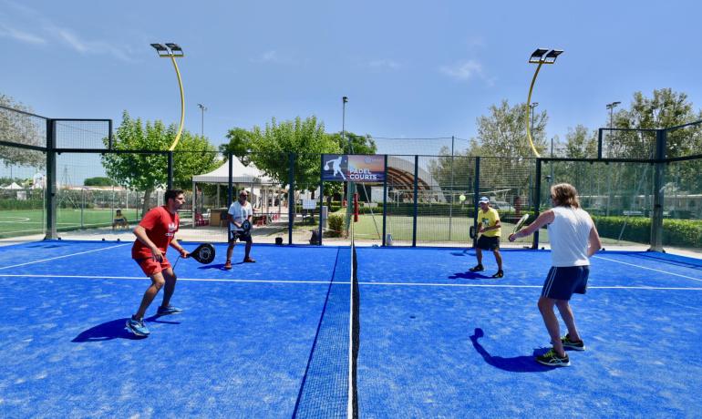 Vier Personen spielen Padel auf einem blauen Außenplatz.