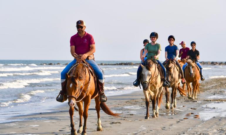 Menschen reiten am Strand und genießen einen sonnigen Tag.