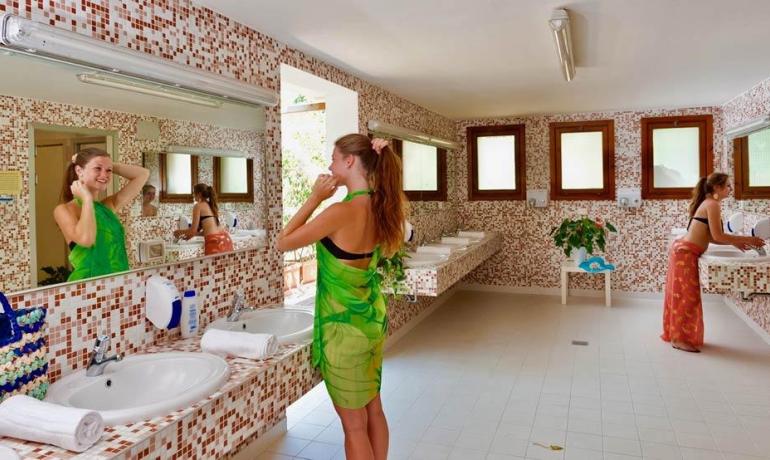 Due donne si preparano in un bagno con piastrelle colorate.
