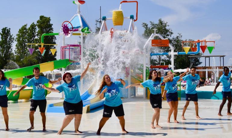 Persone che ballano in un parco acquatico con giochi d'acqua.