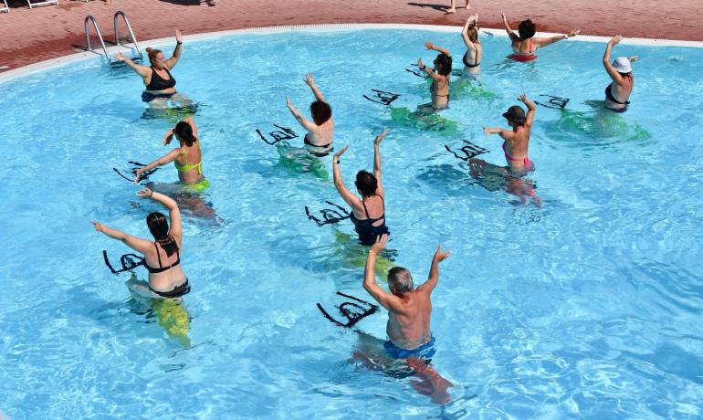 Lezione di acquagym in piscina con istruttore e partecipanti.
