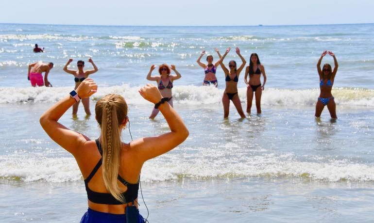 Beach water fitness class with instructor and participants.