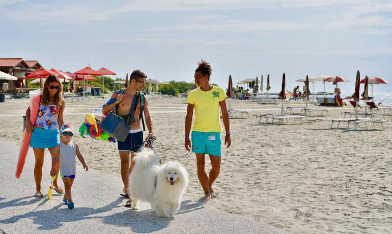 Famiglia in spiaggia con cane e ombrelloni.