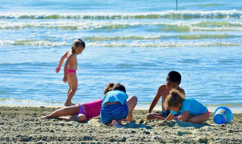 Bambini giocano sulla spiaggia, costruendo castelli di sabbia.