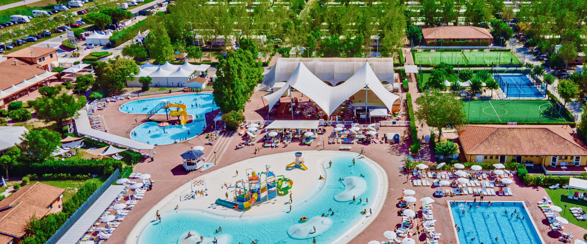 Villaggio turistico con piscine, scivoli e spiaggia immerso nel verde, fronte mare.