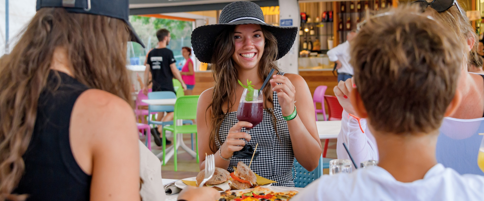 Smiling friends in a colorful restaurant, joyfully toasting.