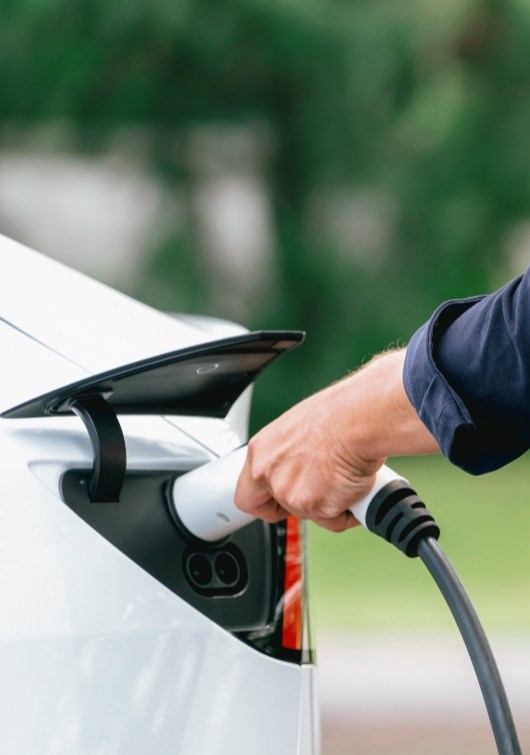 Ricarica di un'auto elettrica con un cavo presso una stazione di ricarica.
