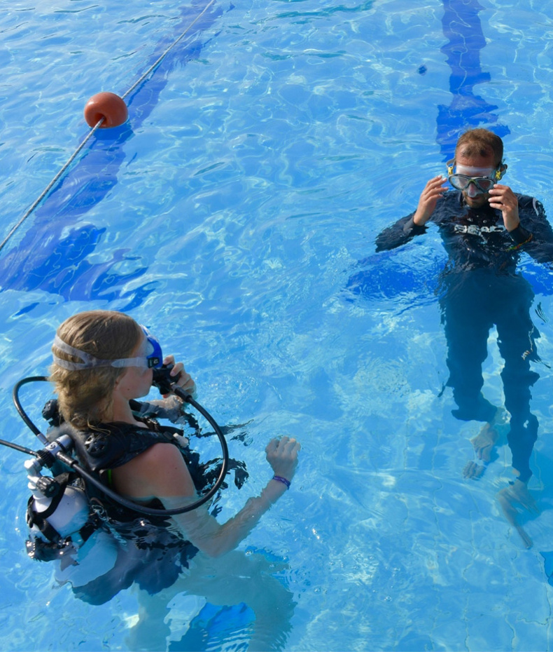 Due bambini e un adulto in piscina con attrezzatura da sub.