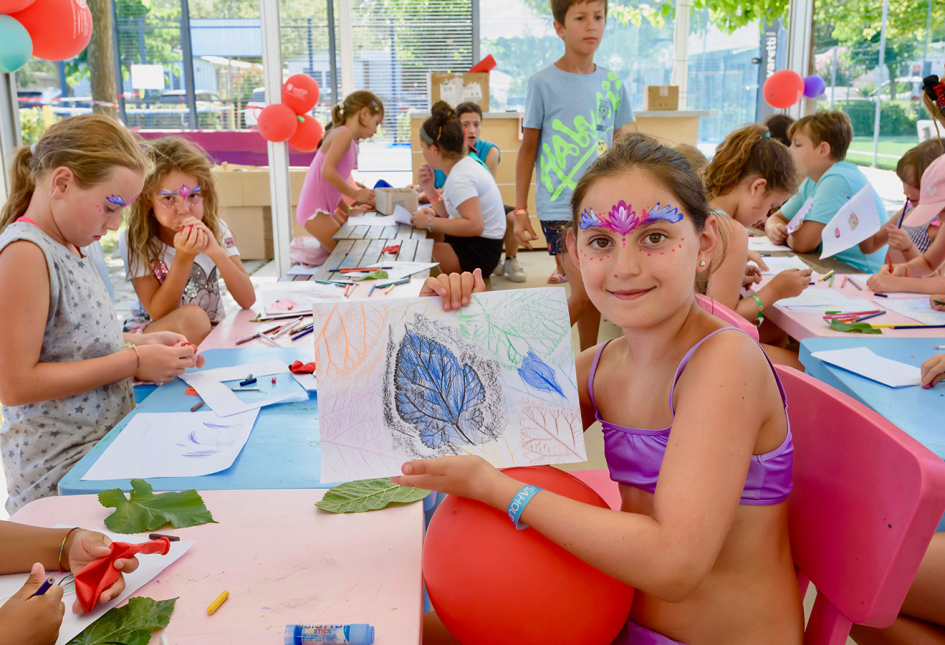 Lezione di acquagym in piscina con molte persone e scivoli sullo sfondo.