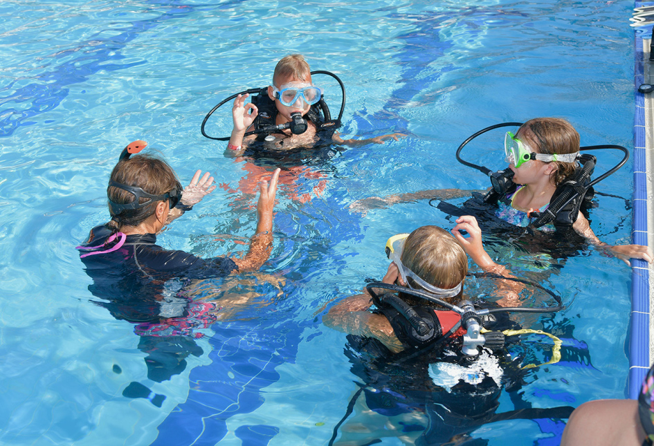 Lezione di immersione subacquea in piscina con istruttore e bambini.