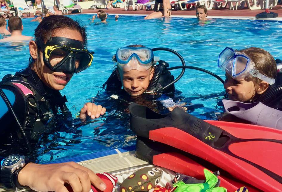 Lezione di immersione subacquea in piscina con istruttore e bambini.