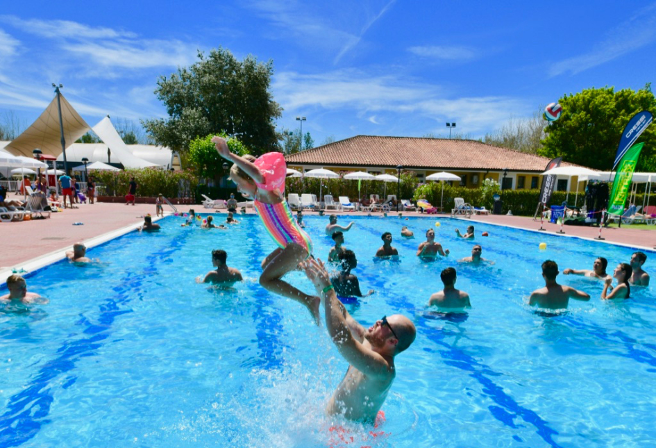 Persone si divertono su uno scivolo d'acqua in un parco acquatico soleggiato.