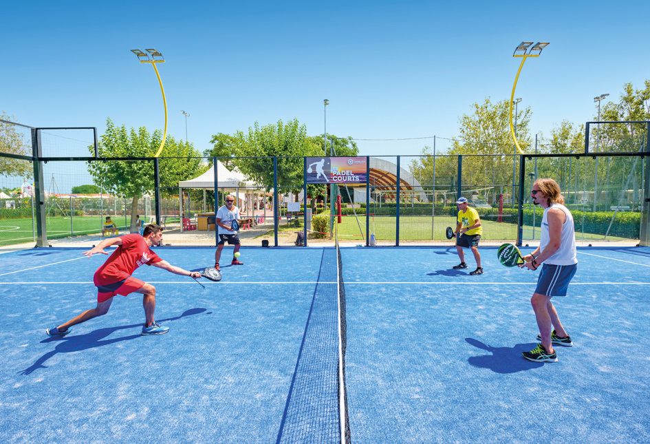 Four friends playing padel on a blue court, energy and fun under the sun.