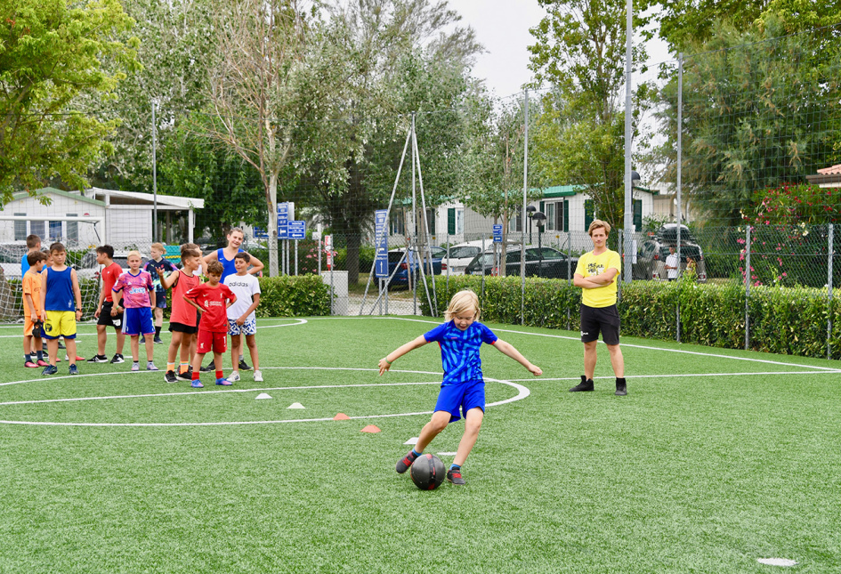 Kids playing soccer, smiles and energy on a green field.